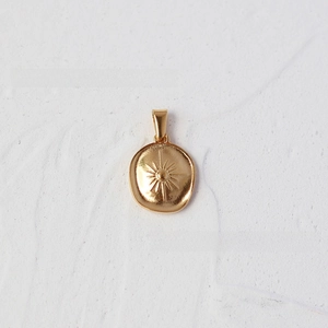 Detailed macro view of 18K gold-plated oval pendant featuring engraved sunburst texture