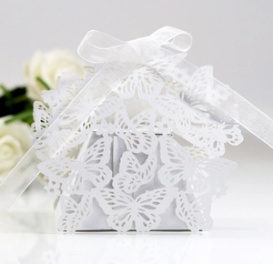 Close-up of white laser-cut butterfly candy box with silk ribbon for wedding party