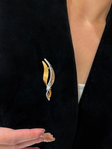 Macro shot of a twisted gold and silver cubic zirconia brooch on a black velvet suit lapel
