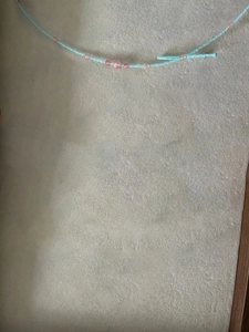 Détail de perles de rocaille bleu clair et rose sur un collier avec texture artisanale