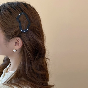 Close-up of a black cut-out star hair clip with white pearl accents on a model