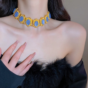 Detail of vintage gold necklace with blue gemstone on model showing neckline fit