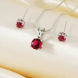 Gros plan d'un ensemble collier et boucles d'oreilles avec pierres rouges sur soie