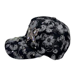 Detail of silver floral embroidery and rainbow rhinestone butterfly on a black baseball cap