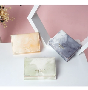 Three slim women's wallets in marble patterns showing orange, gray and green PU leather