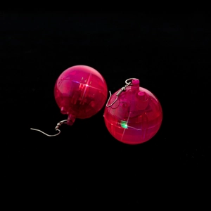 Close-up of pink disco ball earrings with internal LED glow and silver ear hooks