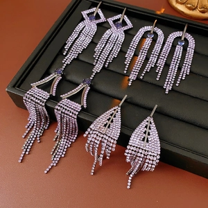 Macro shot of purple rhinestone geometric tassel earrings on a luxury display tray