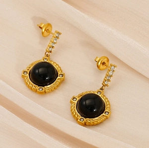 Détail macro de boucles d'oreilles vintage en pierre noire avec cadre doré et zircons