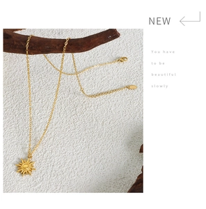 Artistic display of a 18K gold sun pendant necklace hanging on a natural wooden branch