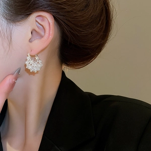 Detailed view of cluster pearl basket earrings in silver finish worn by a model