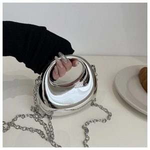 Gros plan d'un mini sac pochette argenté avec poignée ronde intégrée et bandoulière chaîne
