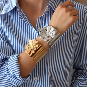 Detail of metallic flower cuff bracelets in gold and silver finish on a model