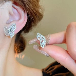 Detail of silver bow earrings with sparkling cubic zirconia and pearls on hand