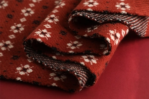Macro shot of red Christmas knit fabric featuring white snowflake patterns and texture