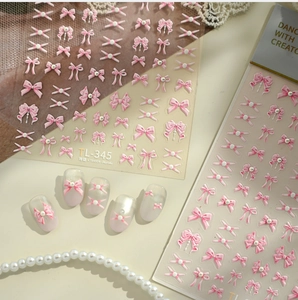 Detailed view of 3D pink bow nail stickers and pearl embossed designs on white nails