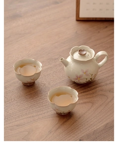 Top view of ceramic teapot and cups with sakura flower patterns on a wooden table