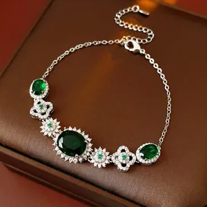 Macro shot of silver bracelet with green emerald stones and clover patterns in jewelry box