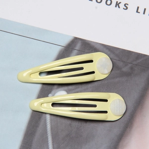 Detail of two light yellow snap hair clips with white circular accents on a magazine