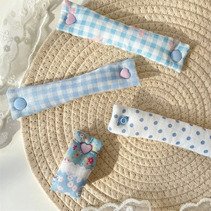 Close-up of floral and plaid fabric cable organizers with heart snaps on a woven mat