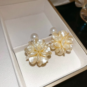 Nahaufnahme der cremefarbenen Kamelien-Ohrringe mit Perlenakzenten in einer Geschenkbox