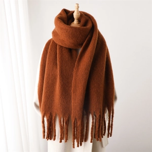 Gros plan détaillé sur la texture de l'écharpe en mohair caramel et les franges longues
