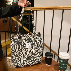 Close-up of zebra print canvas tote bag with letter patches on a wooden cafe table