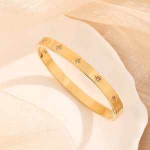 Titanium steel bangle featuring engraved star patterns with cubic zirconia on a ceramic plate