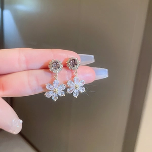 Detailed close-up of a zircon flower earring with purple gemstone and gold plating