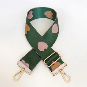 Detail of dark green nylon strap with pink heart jacquard and gold metal buckles