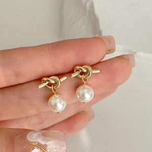 Elegant gold knot stud earrings with lustrous white pearls for a minimalist daily look