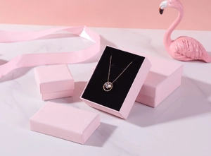 Pink jewelry gift boxes with gold heart necklace on elegant white marble surface