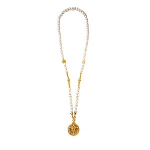 Macro detail of pearl necklace featuring hollow golden disc pendant with gemstone inlay