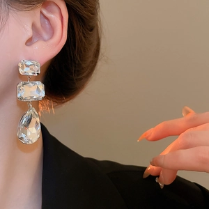 Detail view of tiered square and teardrop crystal fringe earrings with silver plating