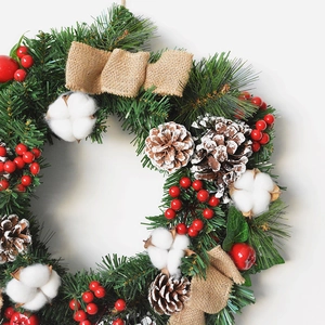 Christmas wreath with pine needles, cotton flowers, pine cones and red berries on white background