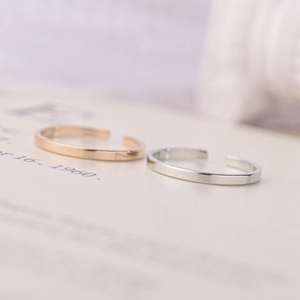 Detailed view of adjustable rose gold and silver stainless steel rings on a book