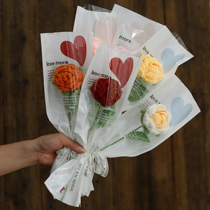 Handcrafted crochet rose bouquet with orange and red flowers in a clear gift wrap