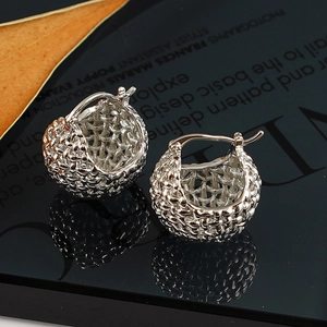 Macro view of French chic silver hollow woven sphere earrings on a black reflective surface