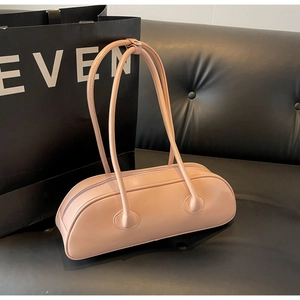 Detail view of pink PU leather baguette bag with thin shoulder straps on a sofa