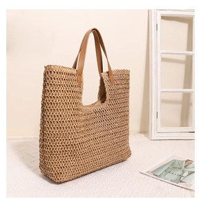 Close-up of woven straw tote bag texture with premium brown leather straps and fabric lining