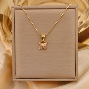 Close-up of golden butterfly pendant with pink crystals in a beige jewelry box