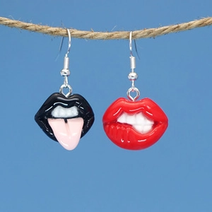 Detail shot of quirky lip-shaped earrings hanging on a rope with a light blue background