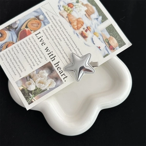 Detailed top view of a silver star hair clip on a white floral ceramic tray