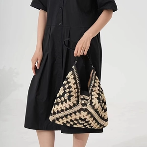Dettaglio di borsa in paglia fatta a mano con motivi geometrici in maglia neri e beige