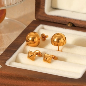 Macro view of geometric 18k gold plated stainless steel dome and pyramid stud earrings