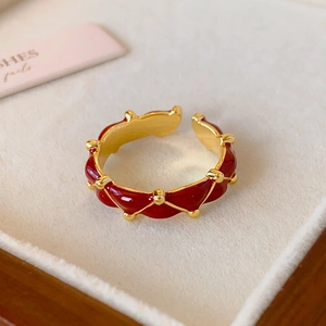 Close-up of 24K gold plated ring with red enamel ripples in a beige jewelry box