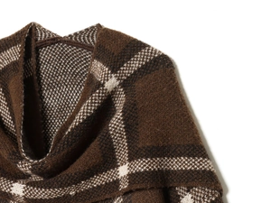 Macro detail of brown and white plaid knit coat showing thick wool yarn texture
