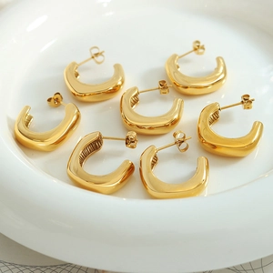 Pendientes de aro dorados en forma de U de acero inoxidable sobre plato blanco