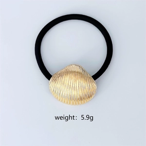 Macro shot of gold seashell hair tie with weight info 5.9g on plain white background