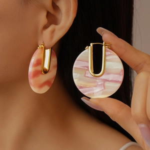 Detail of U-shaped gold earrings with pink marble textured acetate inlay on ear
