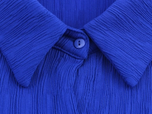 Detail eines blauen Hemdkragens mit strukturierter Plissee-Struktur und Knopf